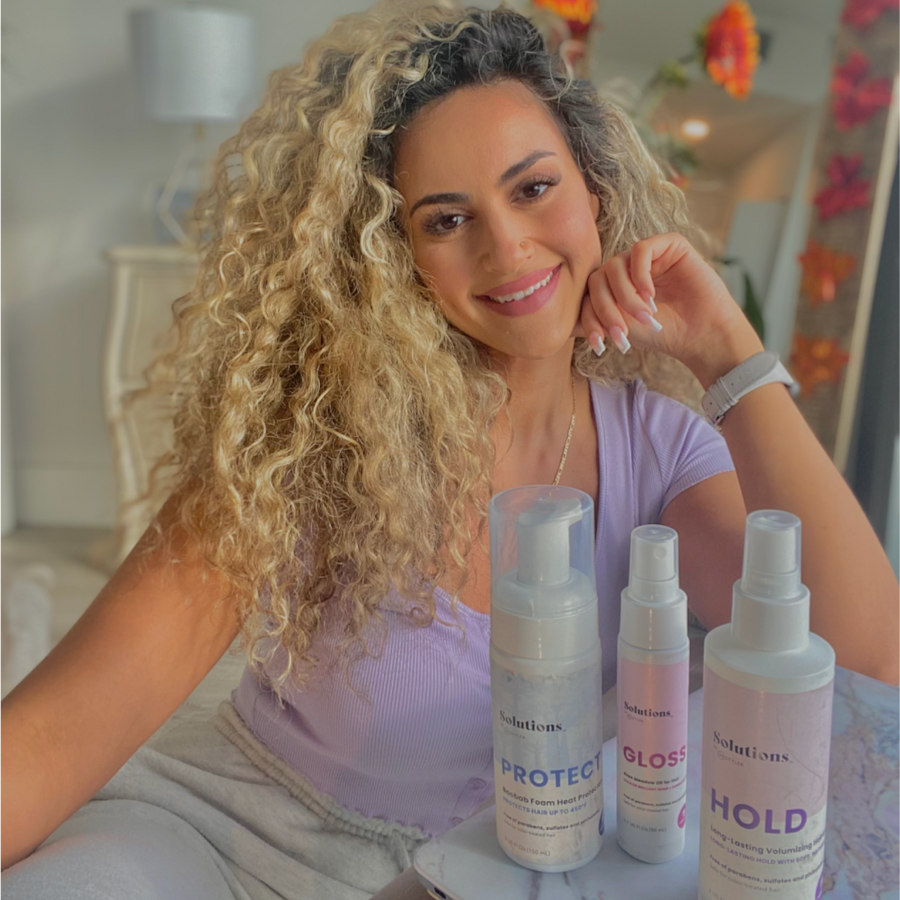 Model with curly blonde hair sitting next to PROTECT Foam Heat Protectant-InStyler