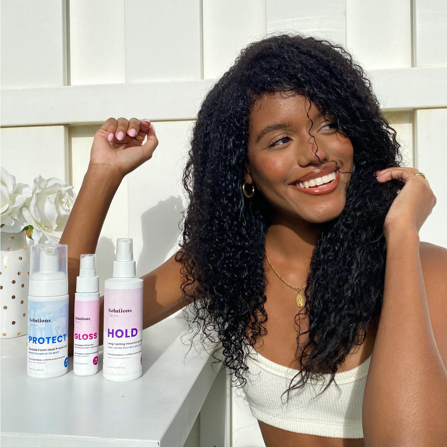 Photo of model with curly black hair sitting next to HOLD Volumizing Hair Spray-InStyler